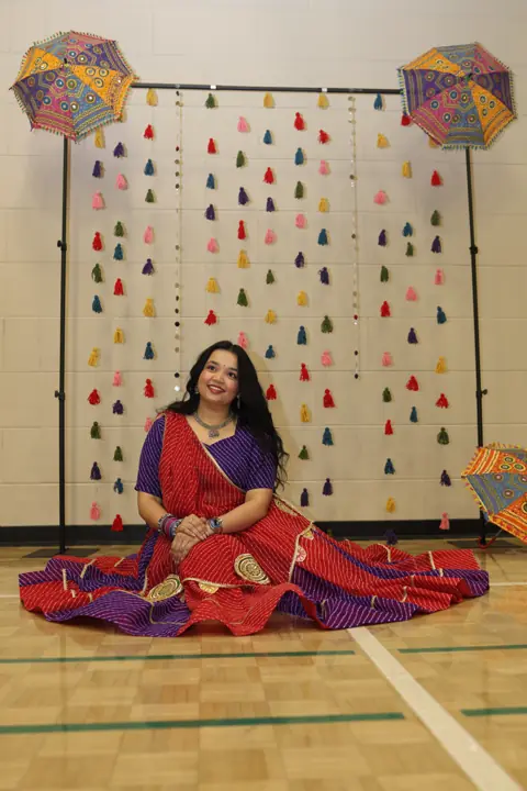 Guest in traditional dress seated beside the Navratri backdrop