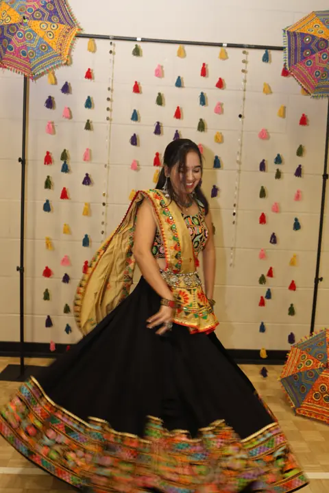 Guest showing traditional dance attire beside the photo backdrop