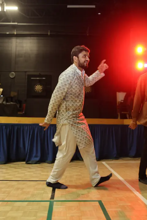 Guest joining the Garba dance under warm event lighting