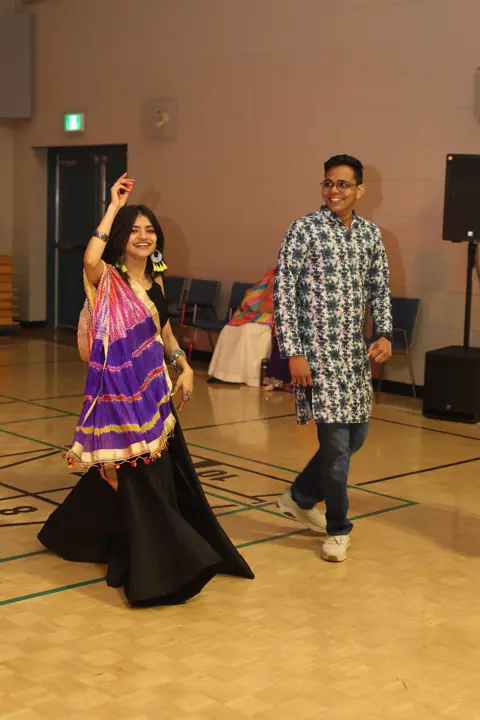 Garba dancers moving together across the hall