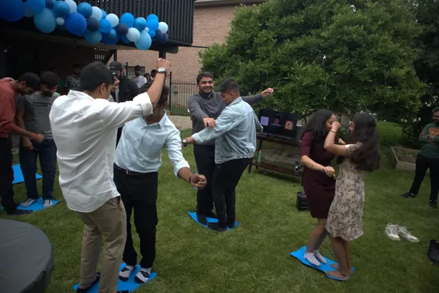 Guests enjoying a garden party game beneath blue balloon decorations