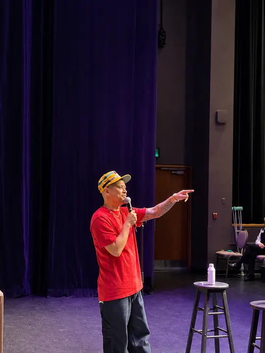 Comedian holding a microphone and pointing towards the audience