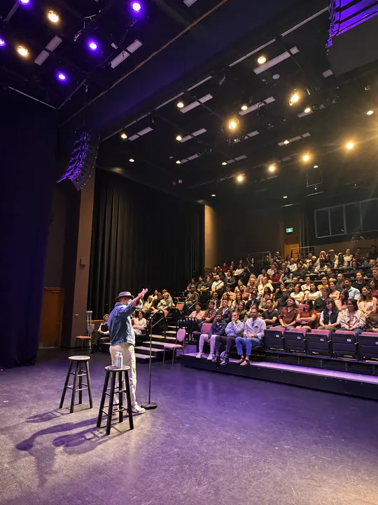 Comedian engaging the audience under theatre stage lights